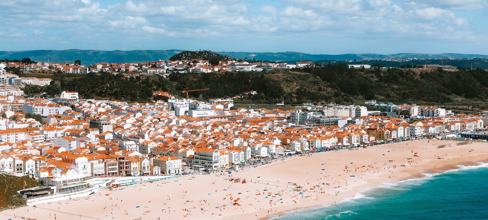An aerial view of Nazaré's terracotta rooftops and pristine beach.
