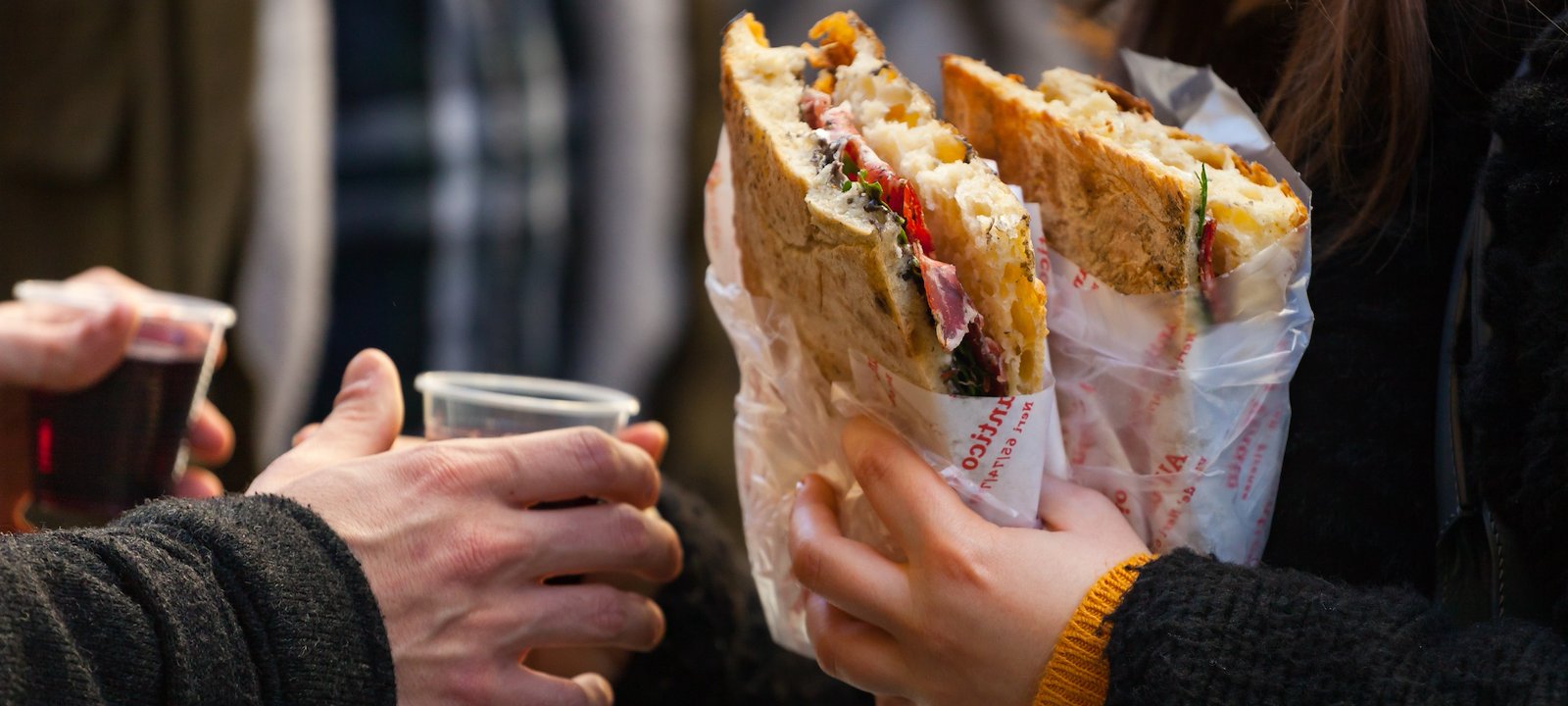 A woman carrying two schiacciata sandwiches from All'Antico Vinaio.