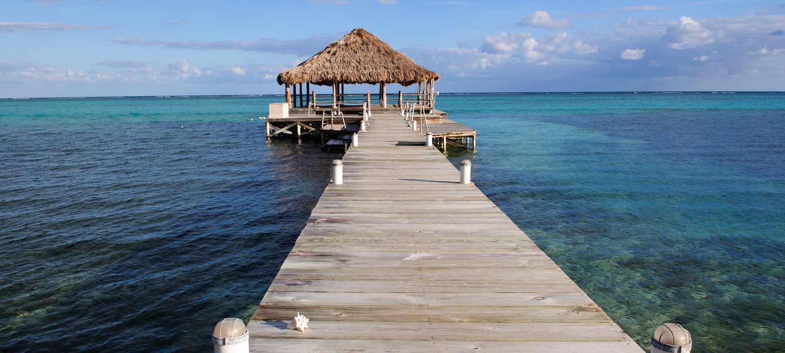 An overwater palapa looks out to the crystal clear waters of the Caribbean.