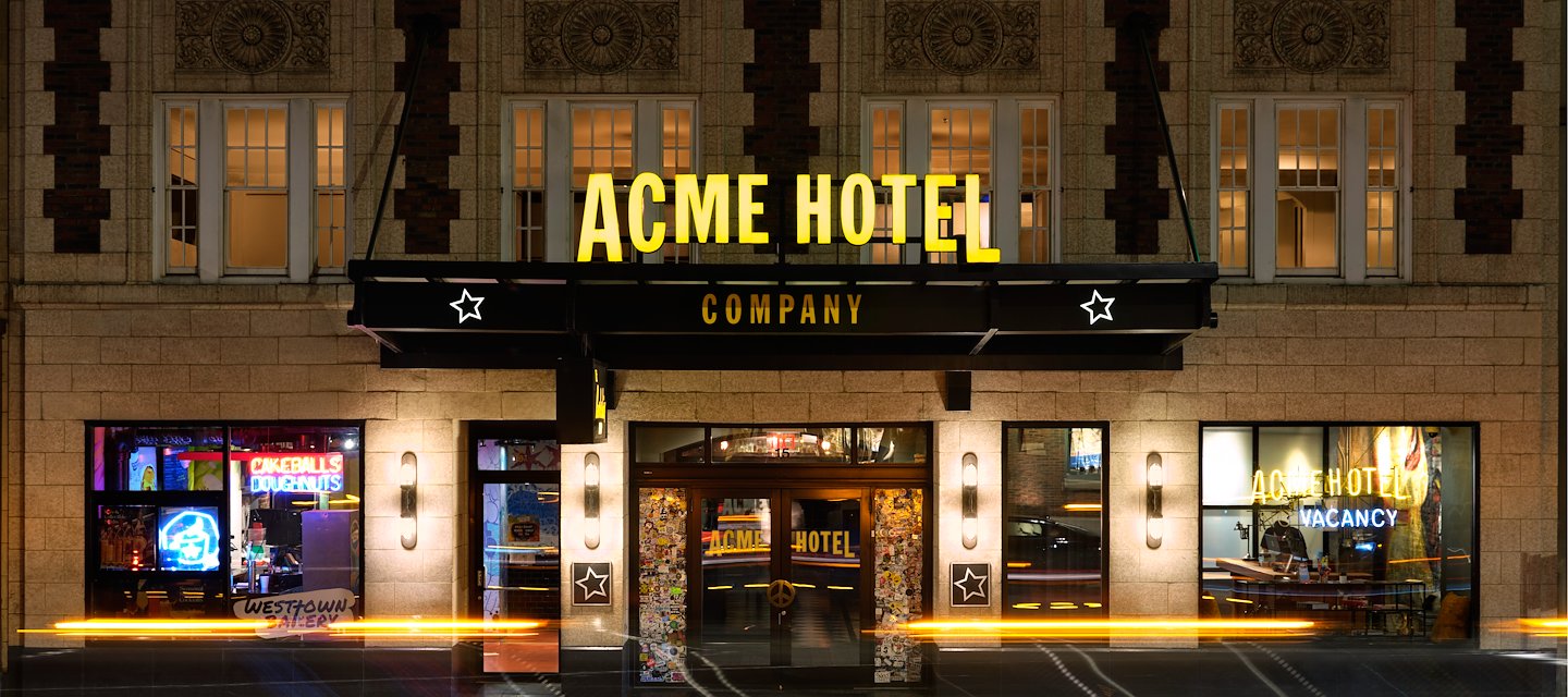 The ACME Hotel in Chicago showcases a vibrant, illuminated façade at night.