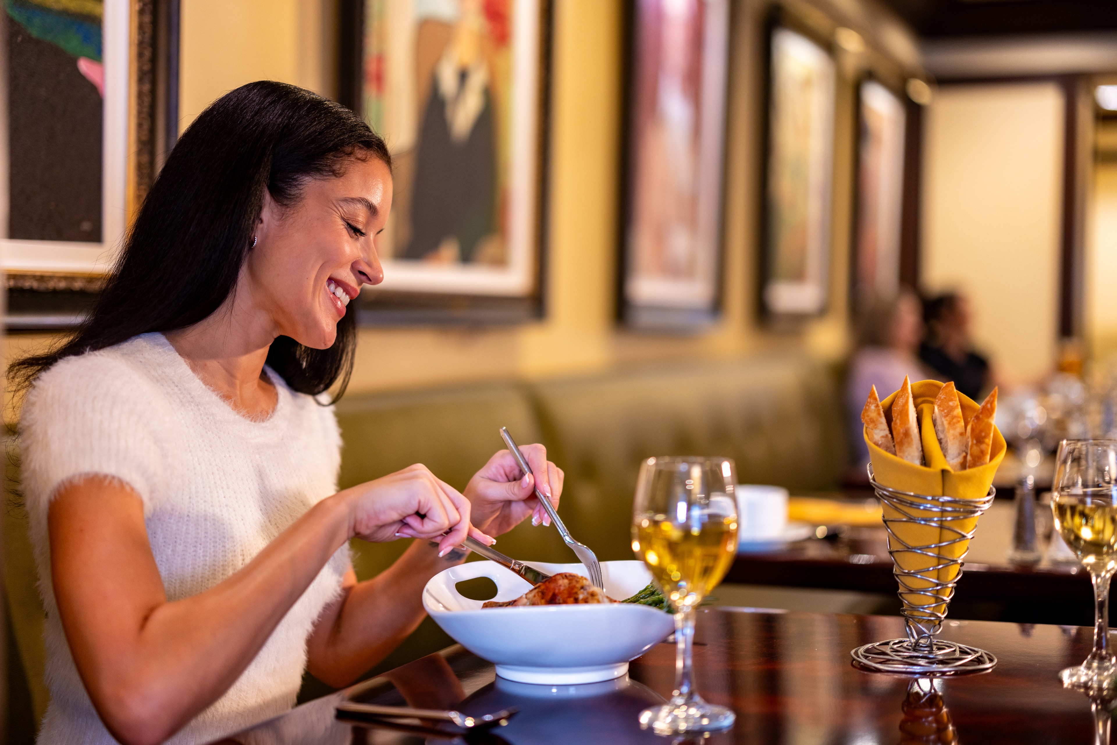 A woman enjoys a meal in a restaurant with art on the walls.