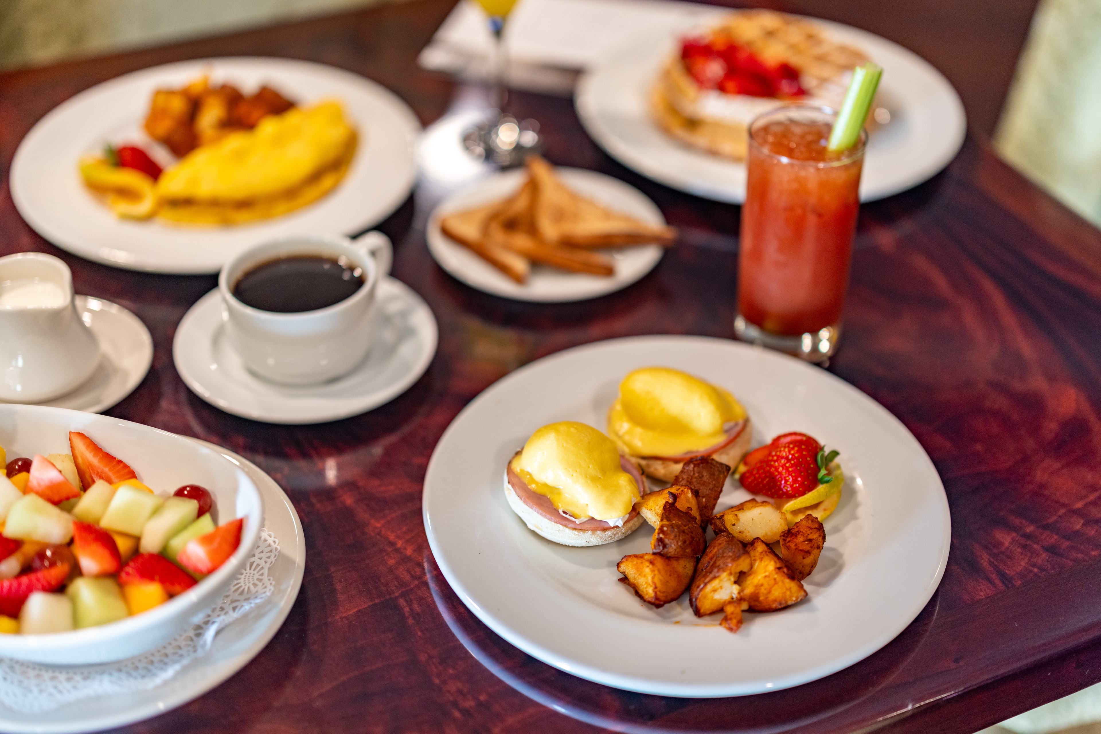 A breakfast table with various dishes, including eggs, toast, fruit, and drinks.