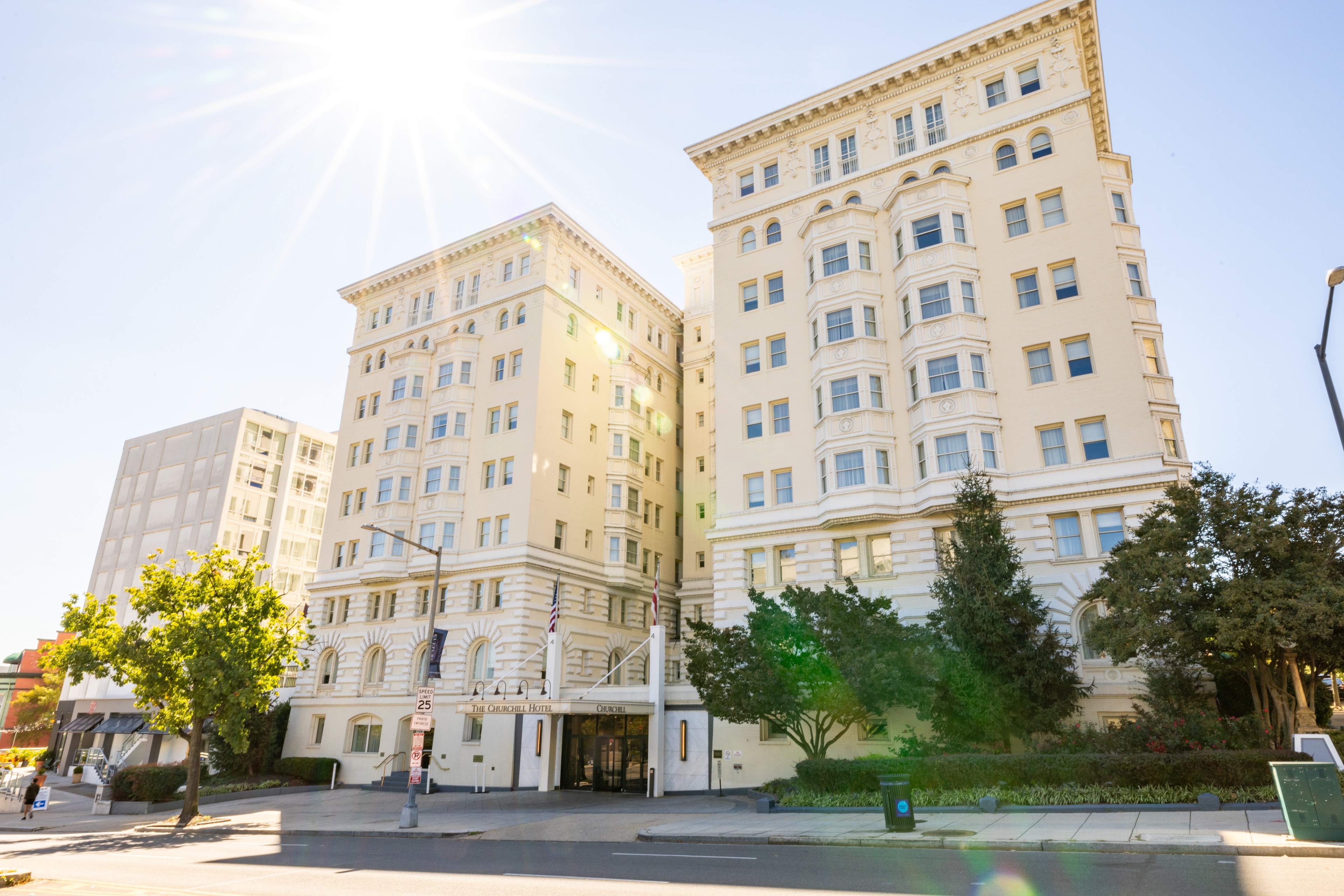 A large beige building with many windows and a tree in front of it.