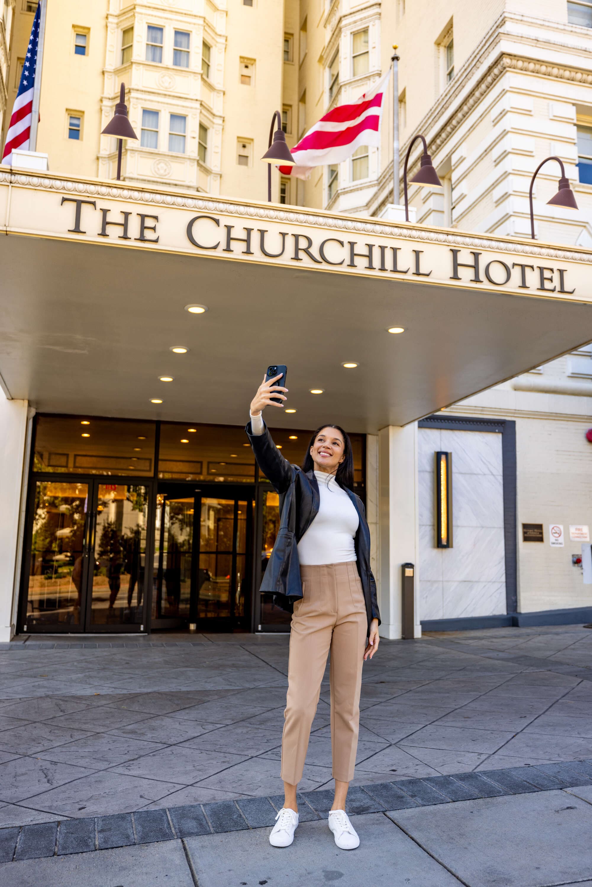 A woman taking a photo in front of The Churchill Hotel entrance