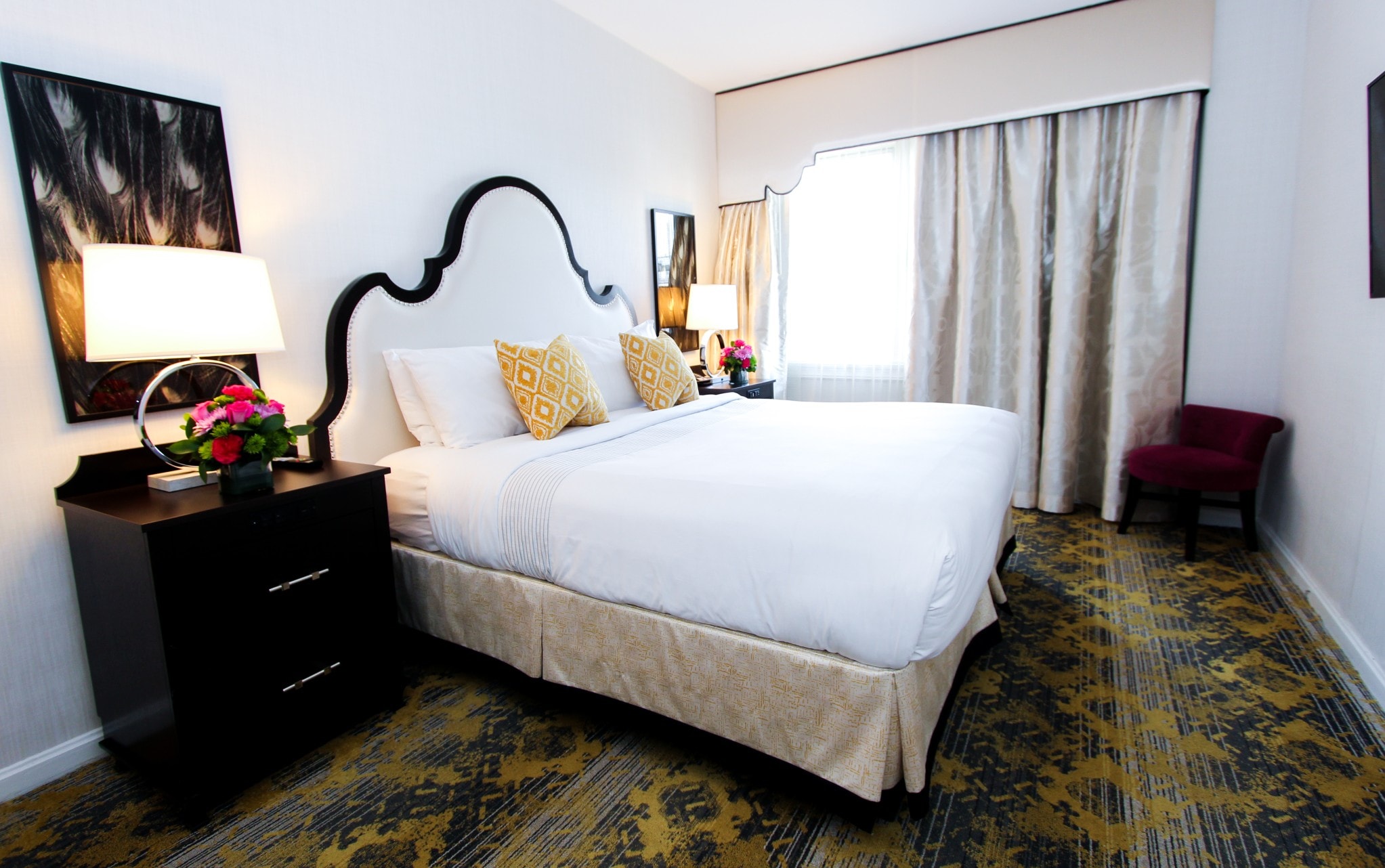 A hotel room with a large bed, nightstand, and window