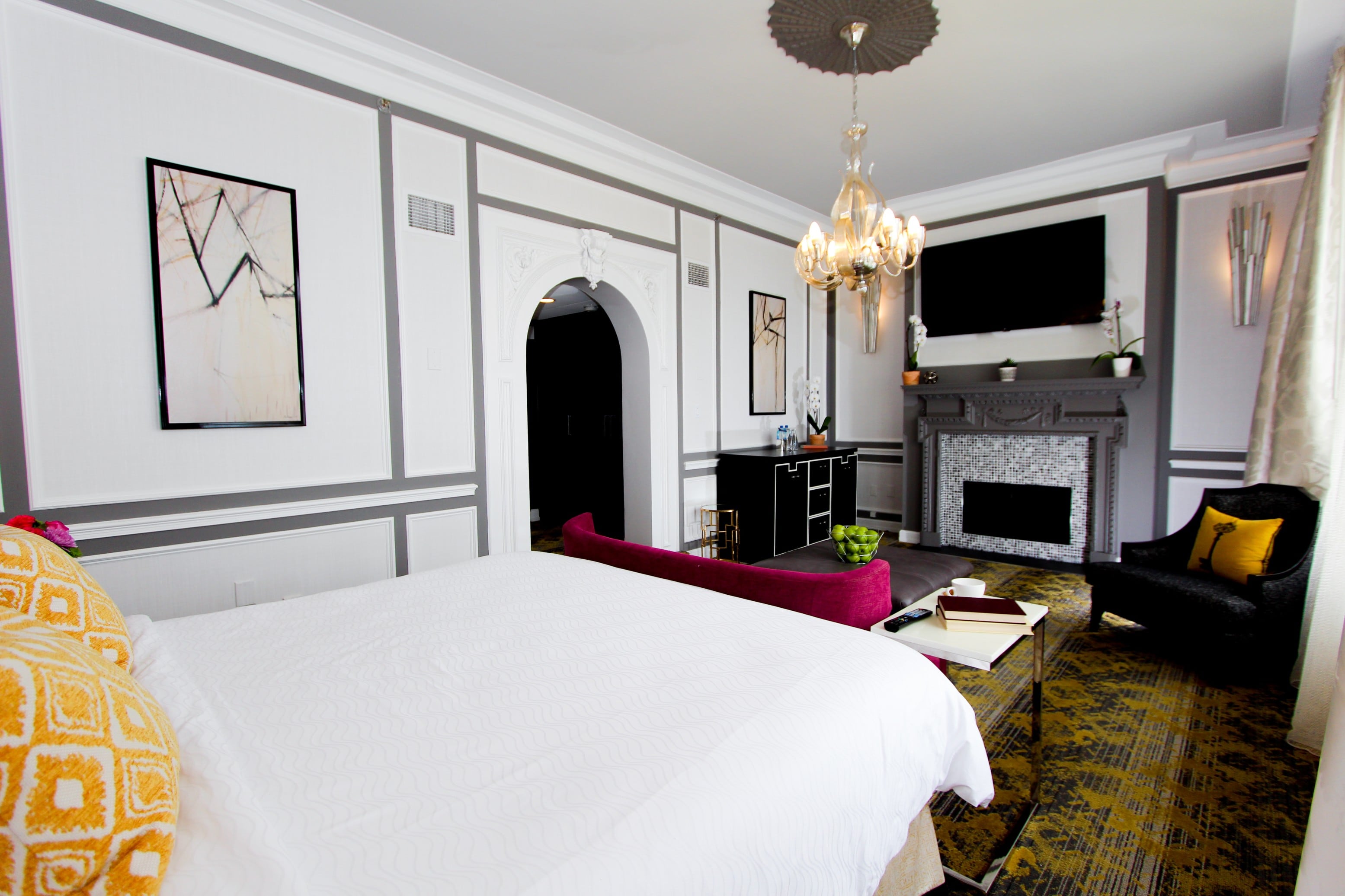 A wide view of a luxurious hotel room with a large bed, sofa, fireplace, and TV.
