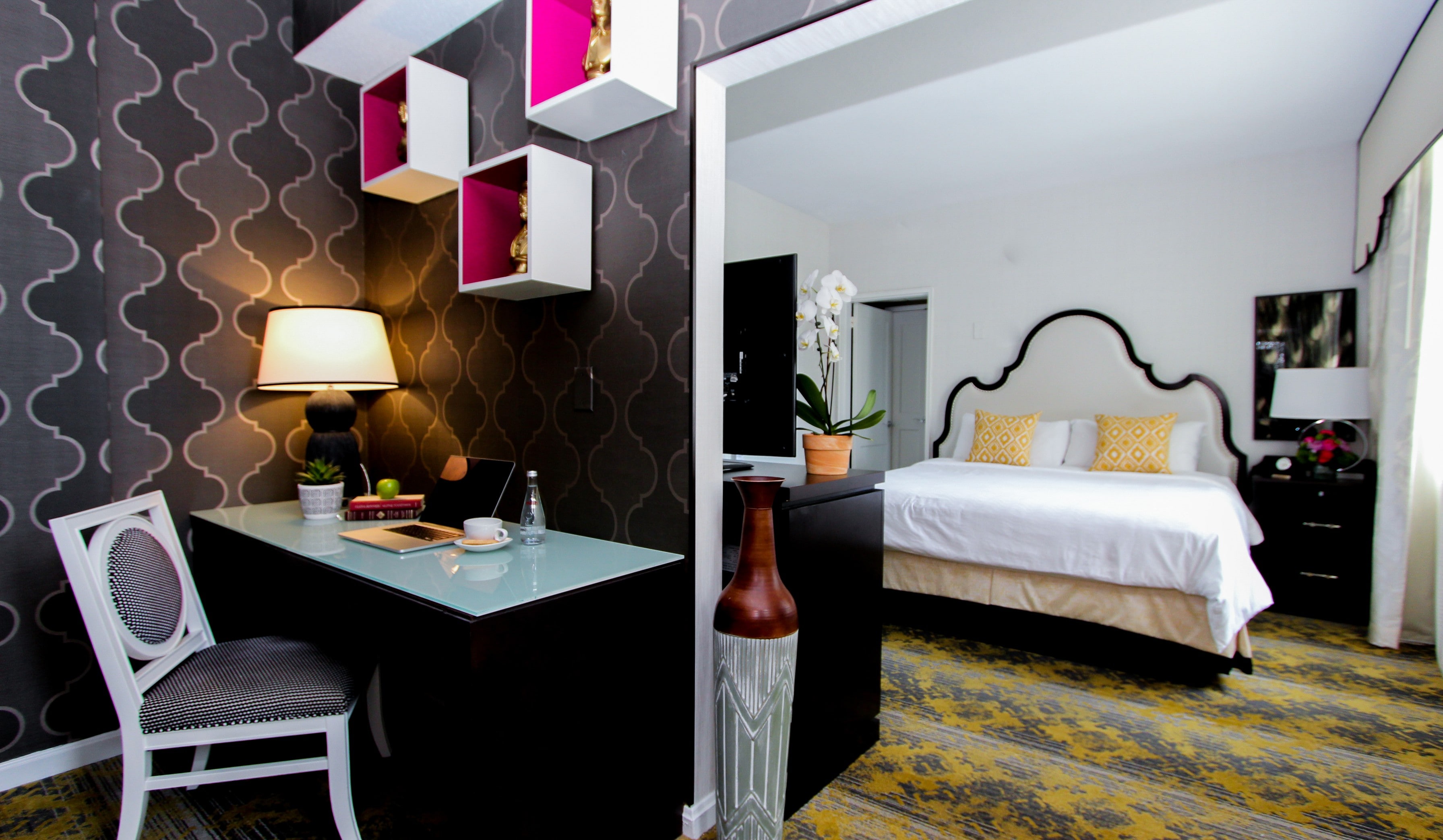A hotel room with a desk, chair, lamp, and bed.