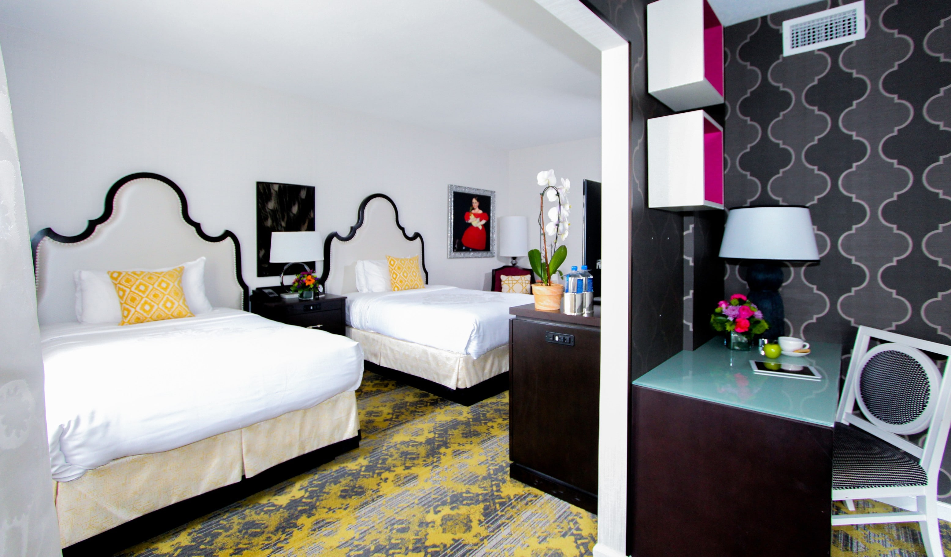 A hotel room with two twin beds, nightstands, and a desk.