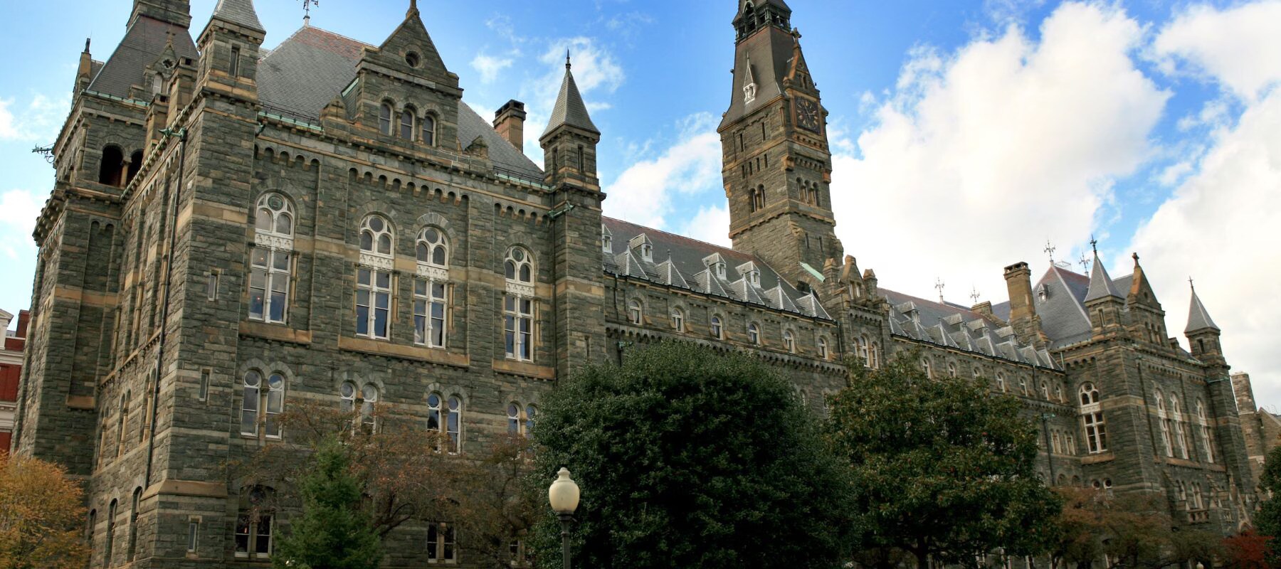 University building with classic architecture, grand columns, and autumn trees on a sunny campus day