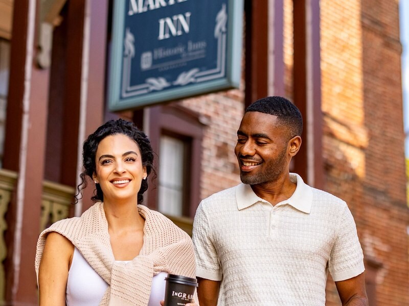 Couple leaving The Maryland Inn with cups of coffee to go