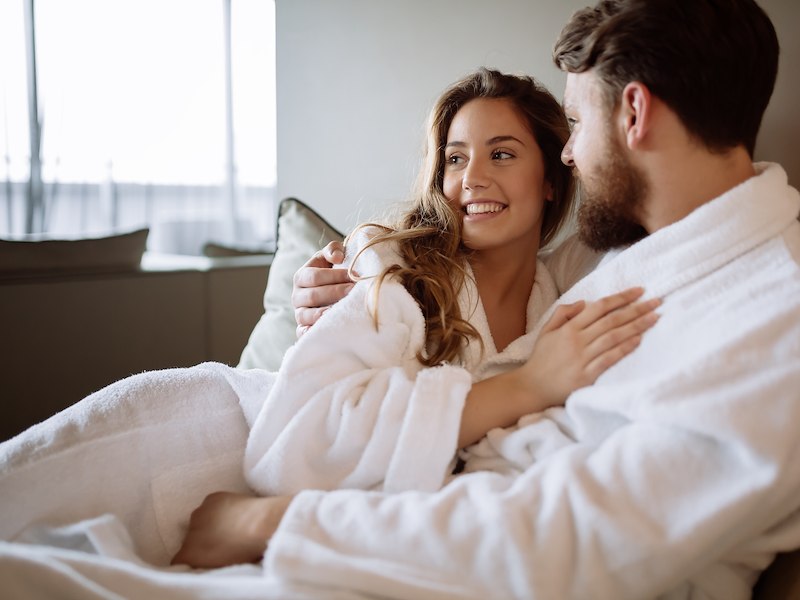 Man and woman cuddling in a hotel room with plush white robes