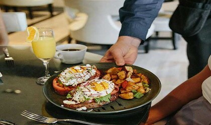 Gourmet brunch with avocado toast, eggs, and roasted potatoes served in a stylish restaurant setting.