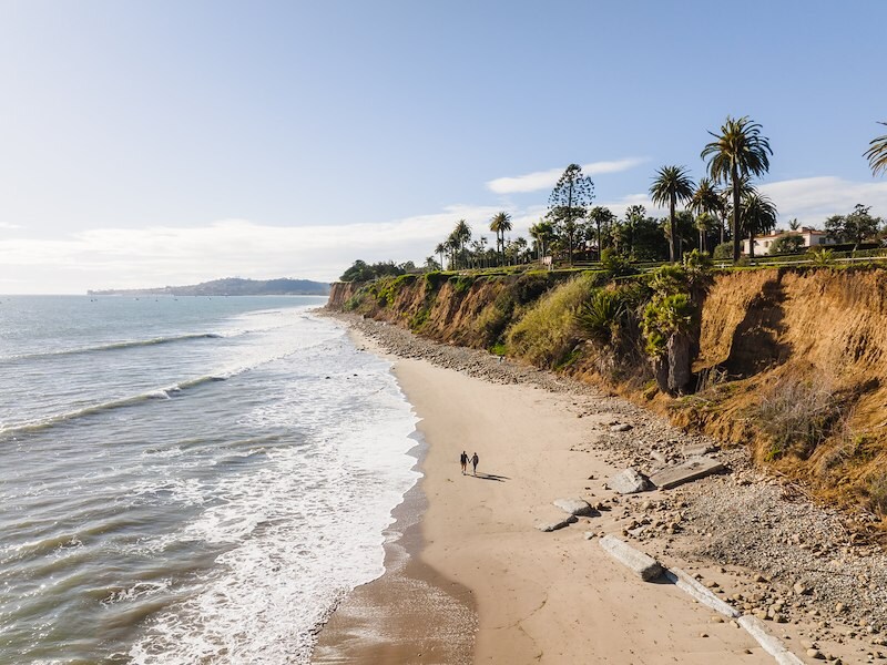 A couple of people walking on a beach