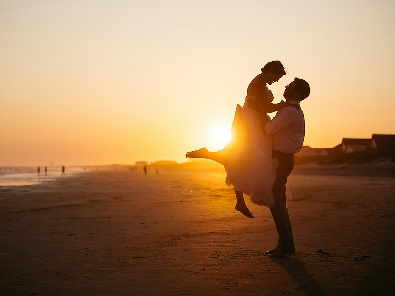 A man holding a woman on the beach