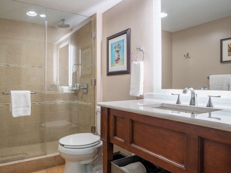 A clean and well-appointed bathroom with a glass-enclosed shower, marble countertop, and wooden cabinetry.