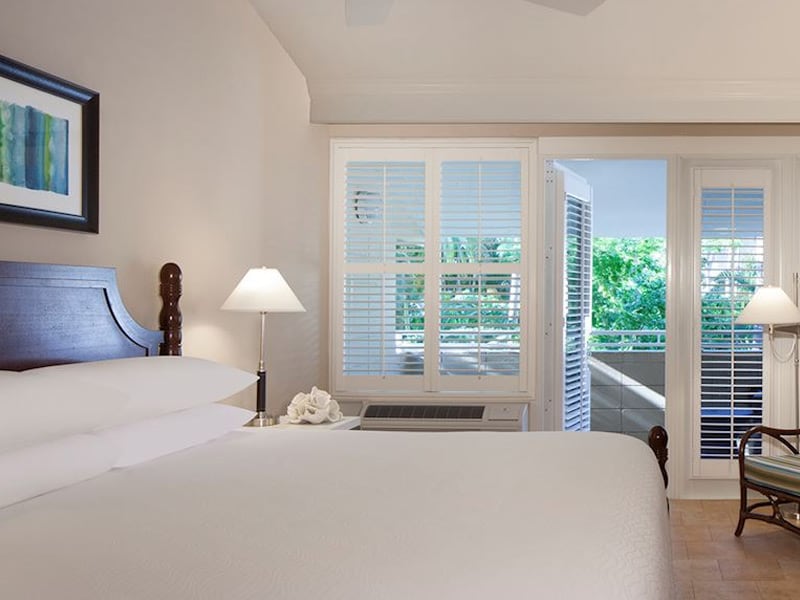 A hotel room with a large bed, two lamps, a piece of artwork, and a balcony door
