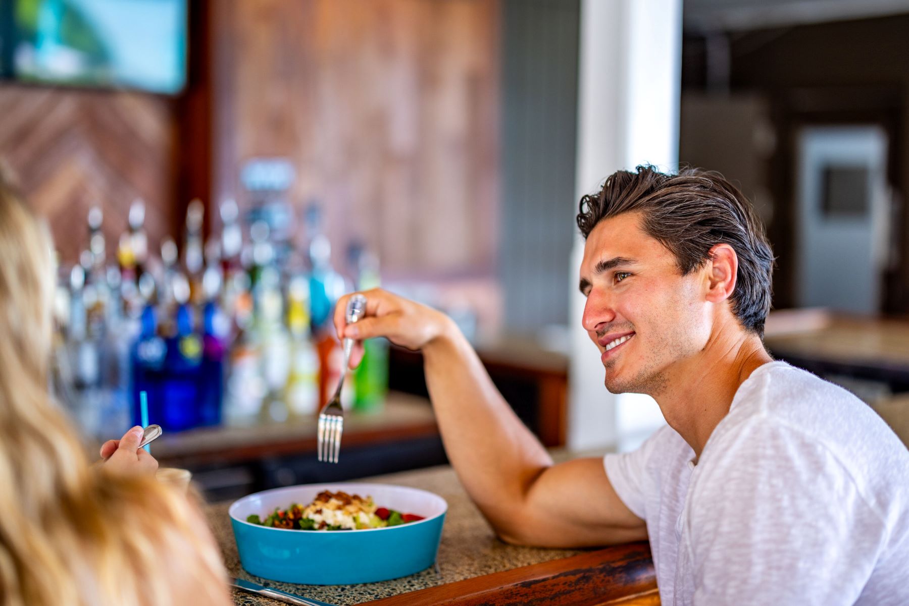 A man and woman sitting at a bar eating
