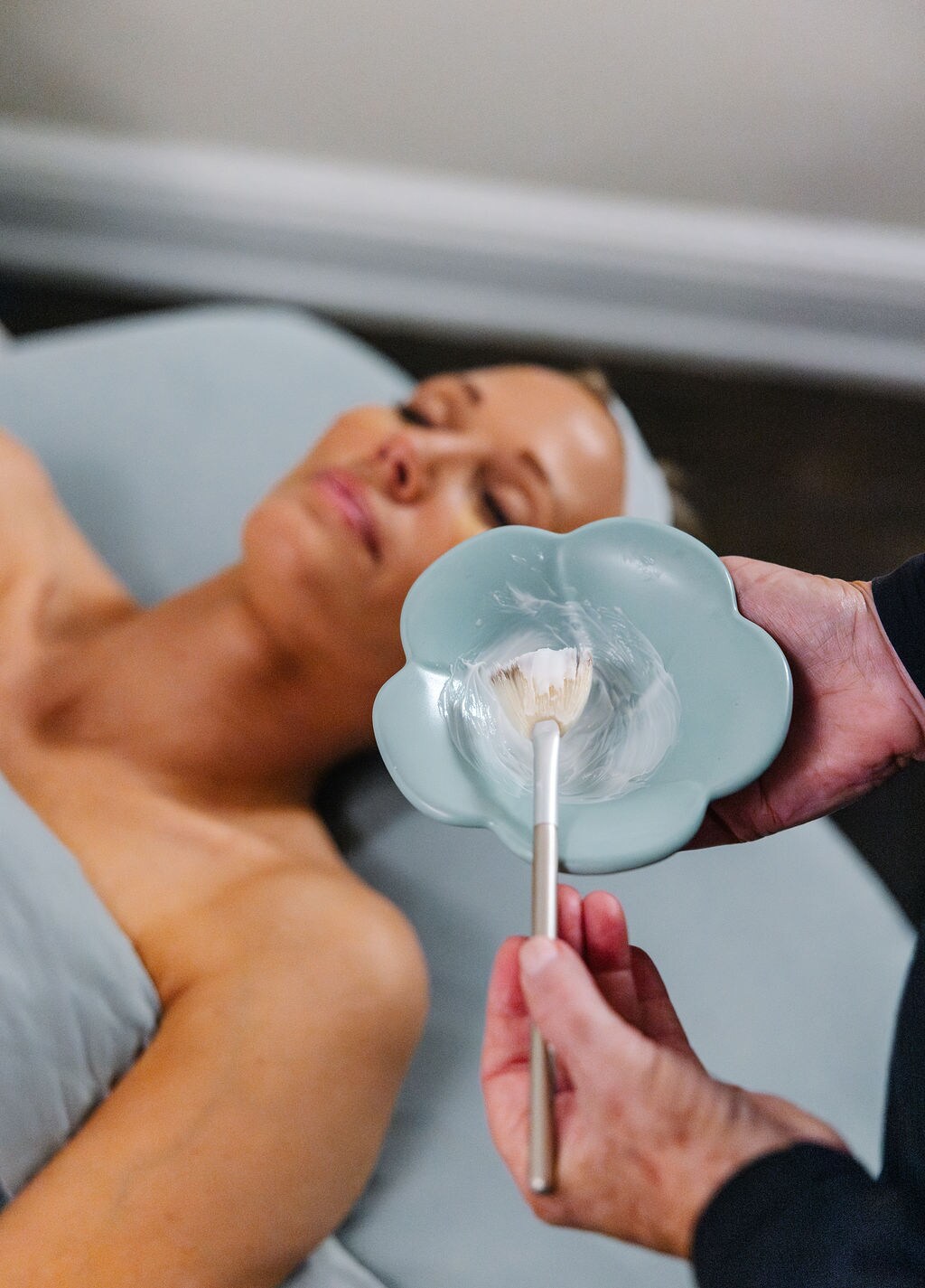 A woman lies on a spa bed receiving a facial treatment