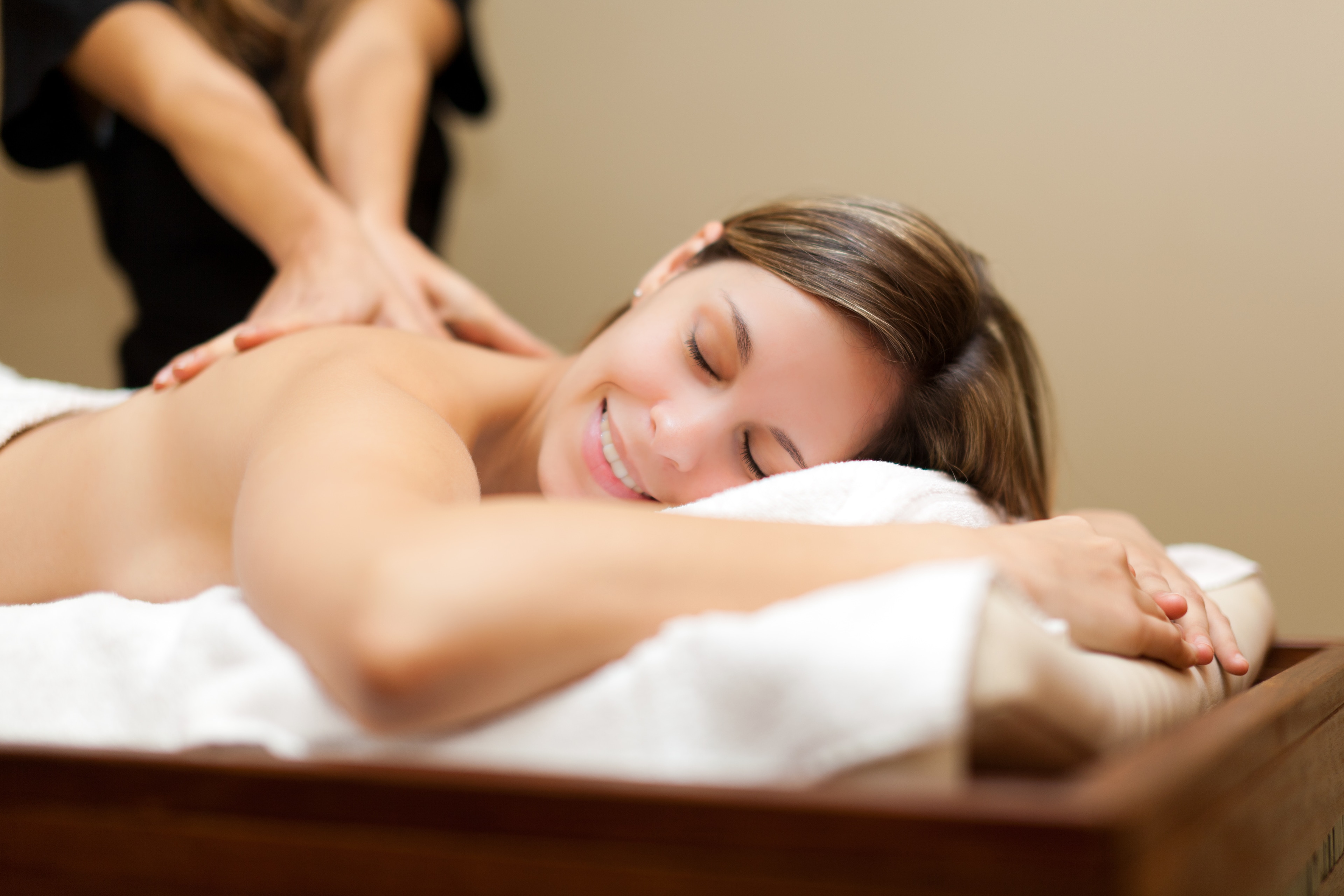 A woman receiving a massage at a spa, with a masseuse working on her back.