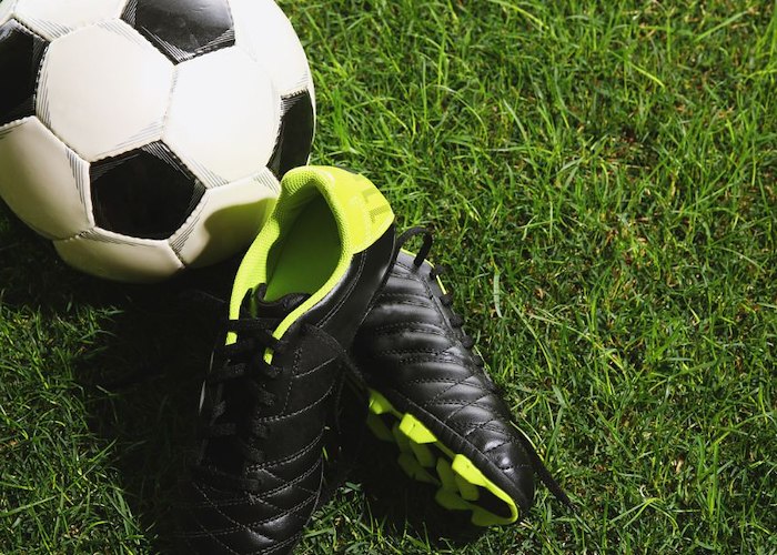A football ball and shoes on grass