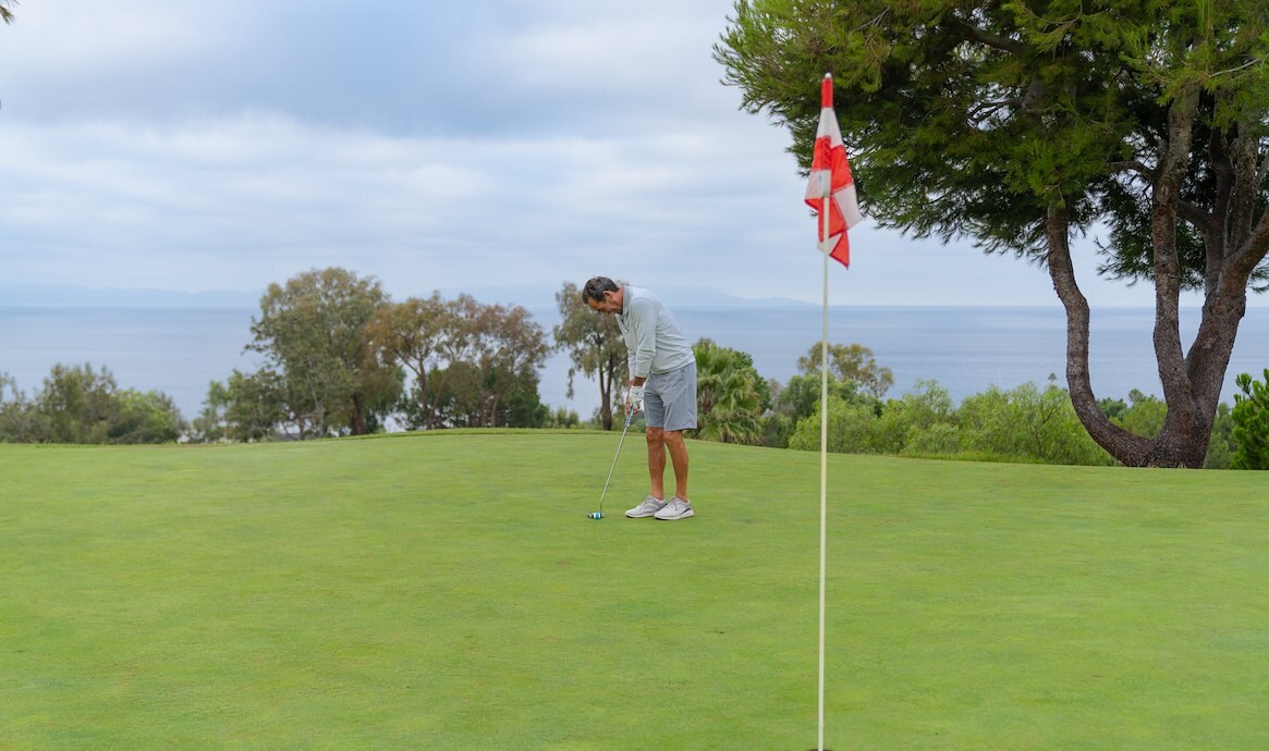 Person golfing at a hole with a flag