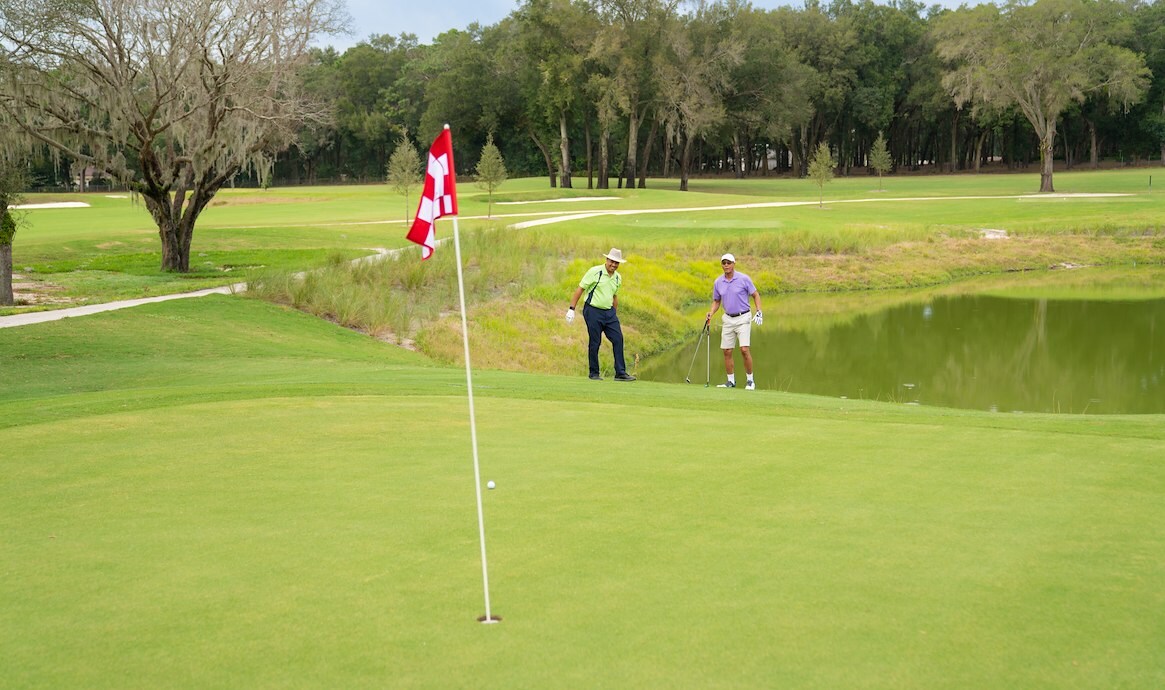 Red and white flag with two golfers in background