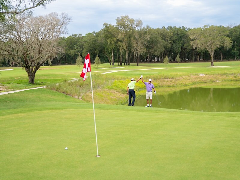 Two men high-fiving at a hole