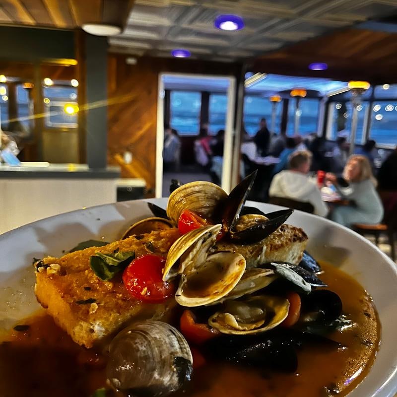 a plate of seafood with clams, mussels, and tomatoes in a broth