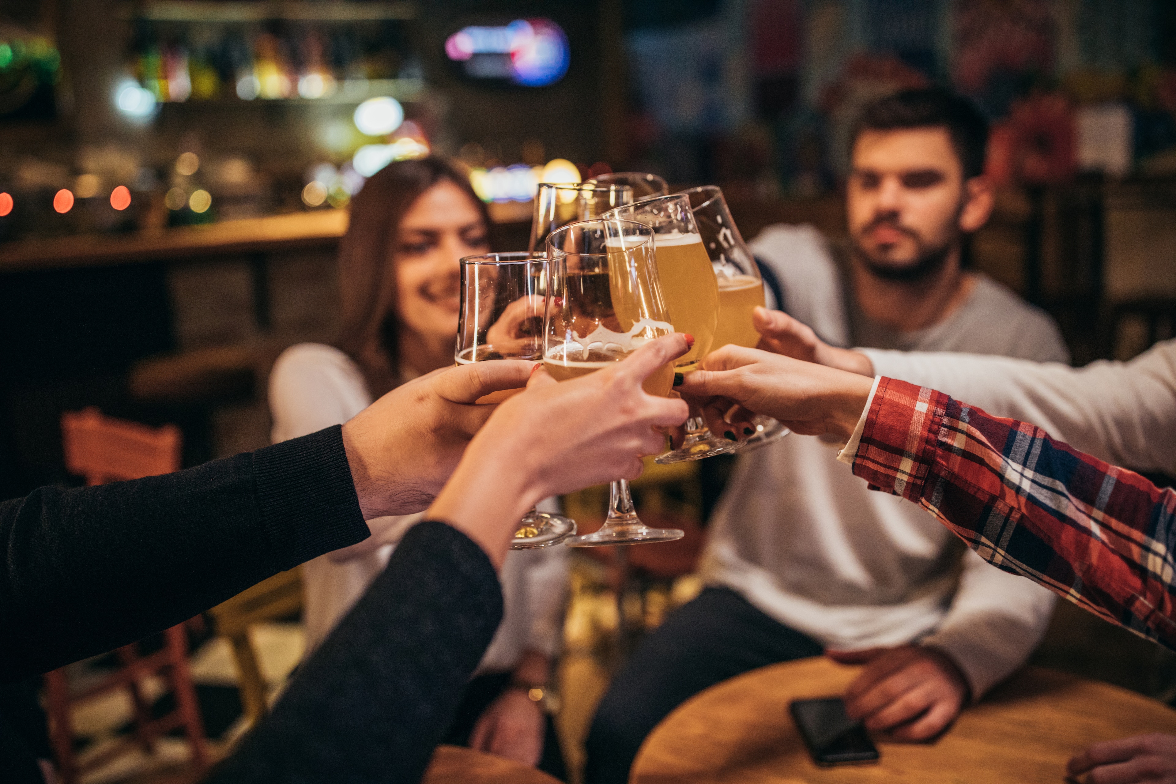 A group of people clinking glasses together at a table in a bar.