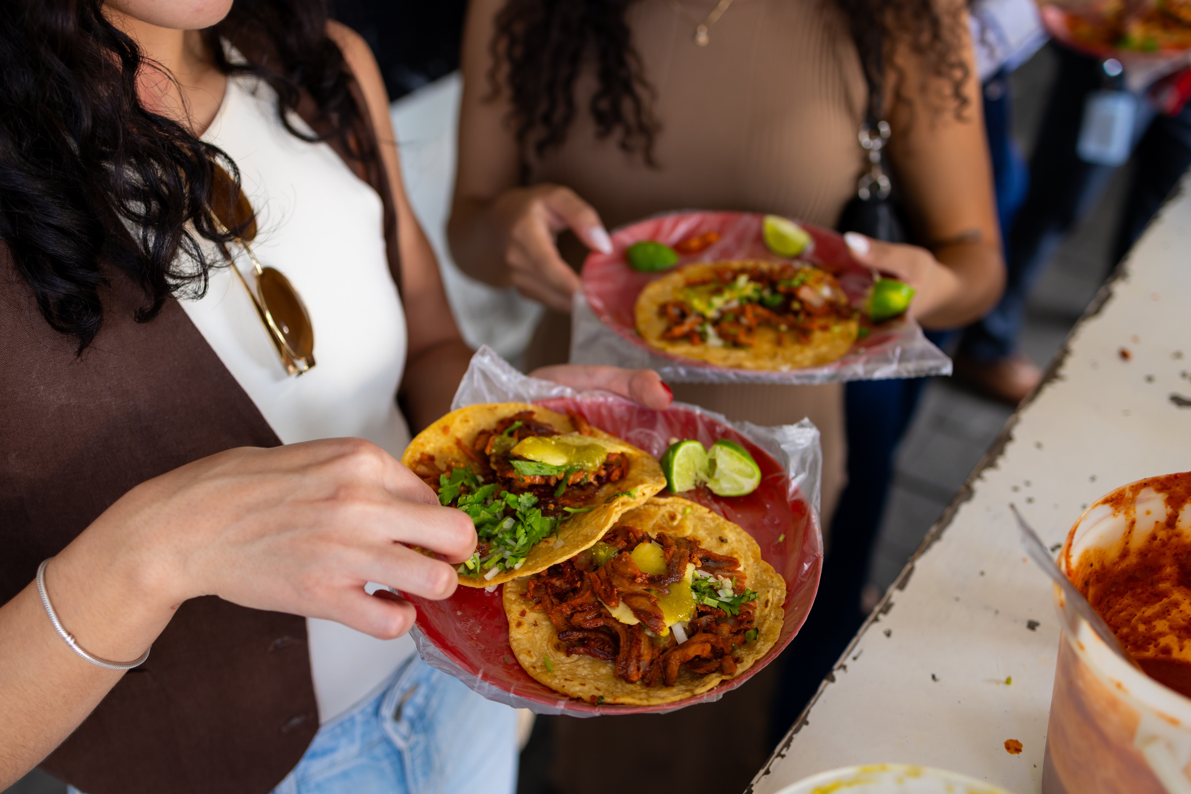 two women holding plates of tacos