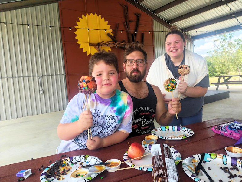 Family enjoying Halloween treats at a picnic table during a camping trip.