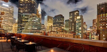 A rooftop terrace with tables and chairs overlooking the city skyline, The Kitano Hotel New York