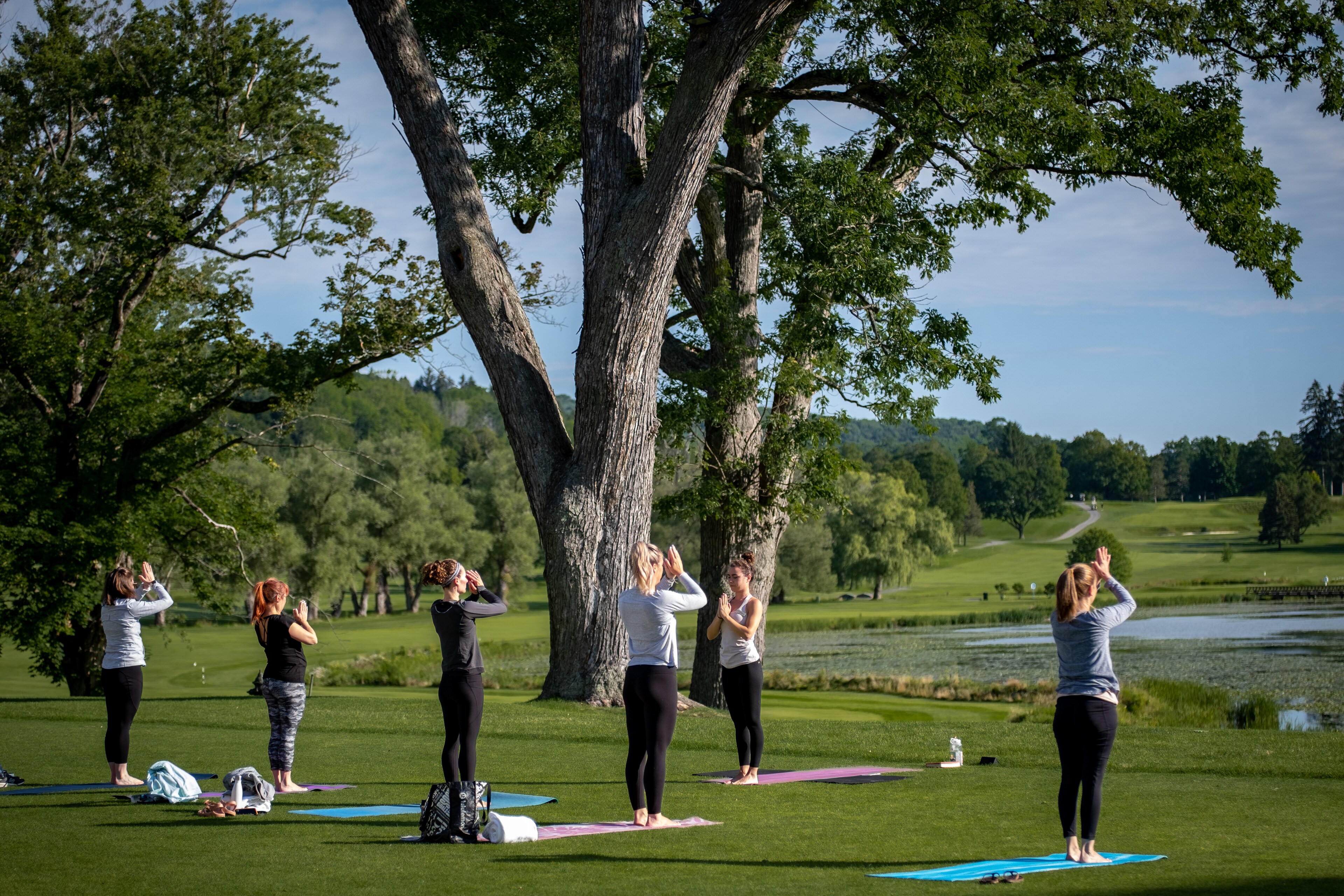Guests practicing yoga by the lake during the Wellness Weekend Package at The Otesaga Resort Hotel, New York
