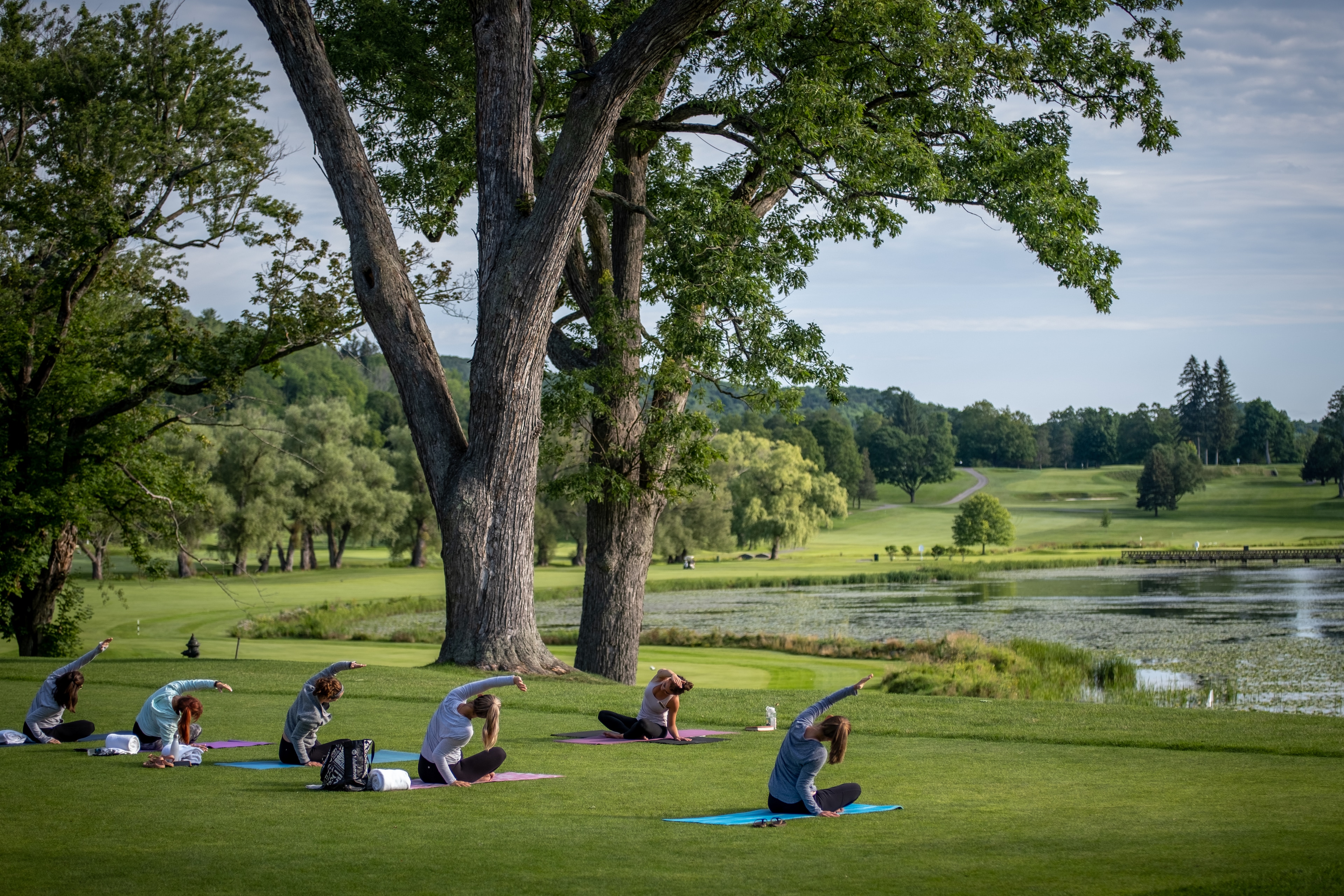 Guests Practicing Yoga By The Lake During A Wellness Healing Retreat For Renewal At The Otesaga Resort Hotel, New York