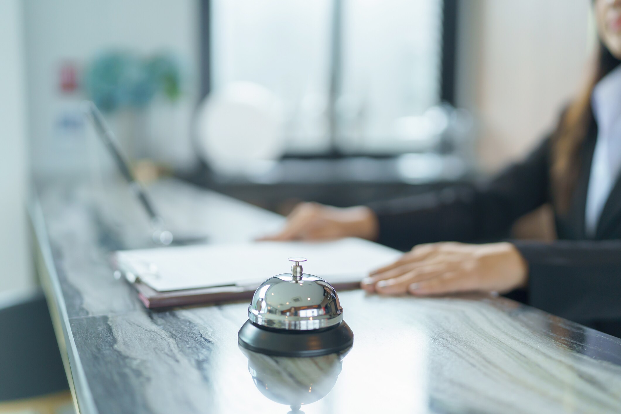 Hotel service bell on reception desk with staff in background in New York