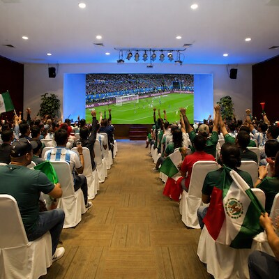 A group of people enjoying a soccer game from the world cup 2026 at The Reef Playacar in Playa del Carmen Mexico