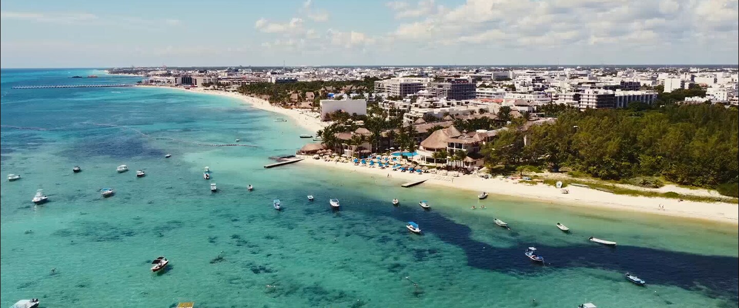 Vista aérea de una playa vibrante con aguas turquesas salpicadas de botes