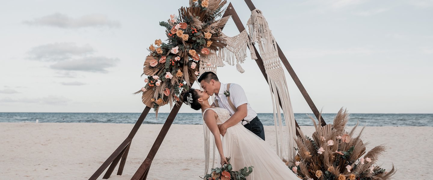 Pareja compartiendo un beso en una ceremonia de boda en The Reef Resorts, Playa Del Carmen.