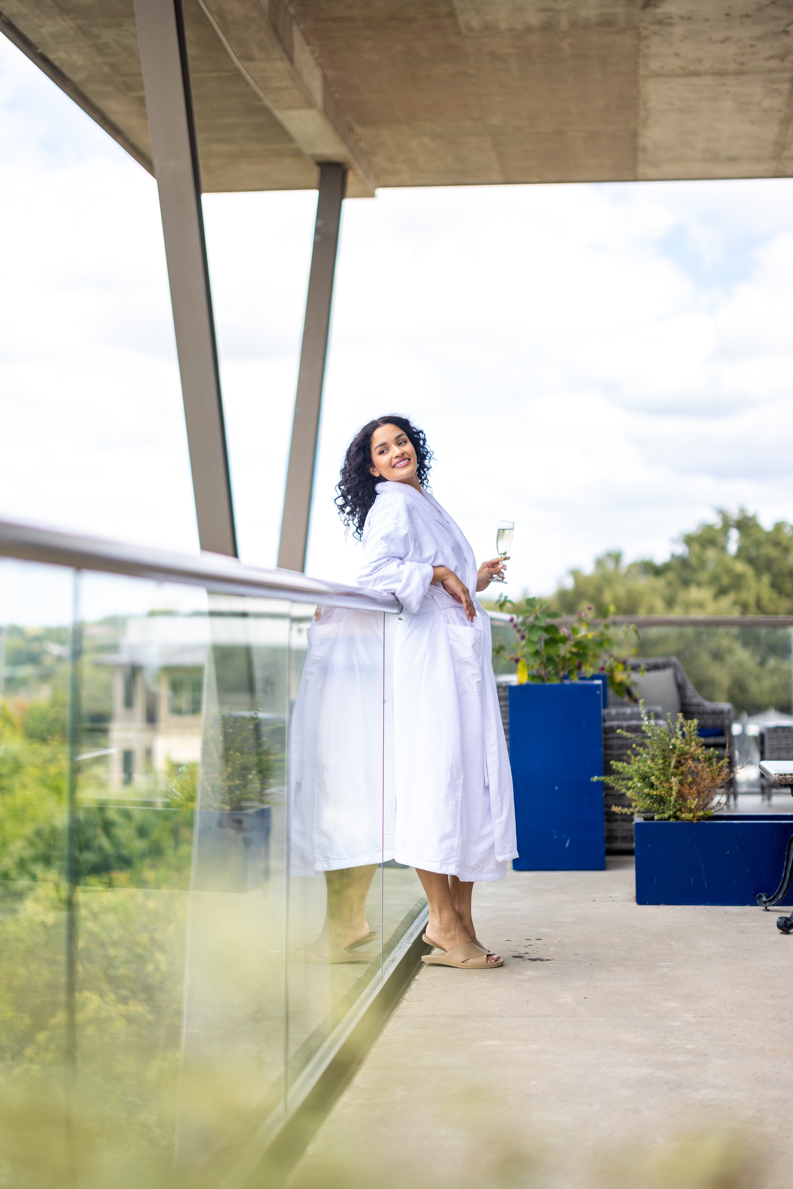 Woman in a white robe standing on a balcony, holding a drink at Lakeway Resort & Spa, Texas