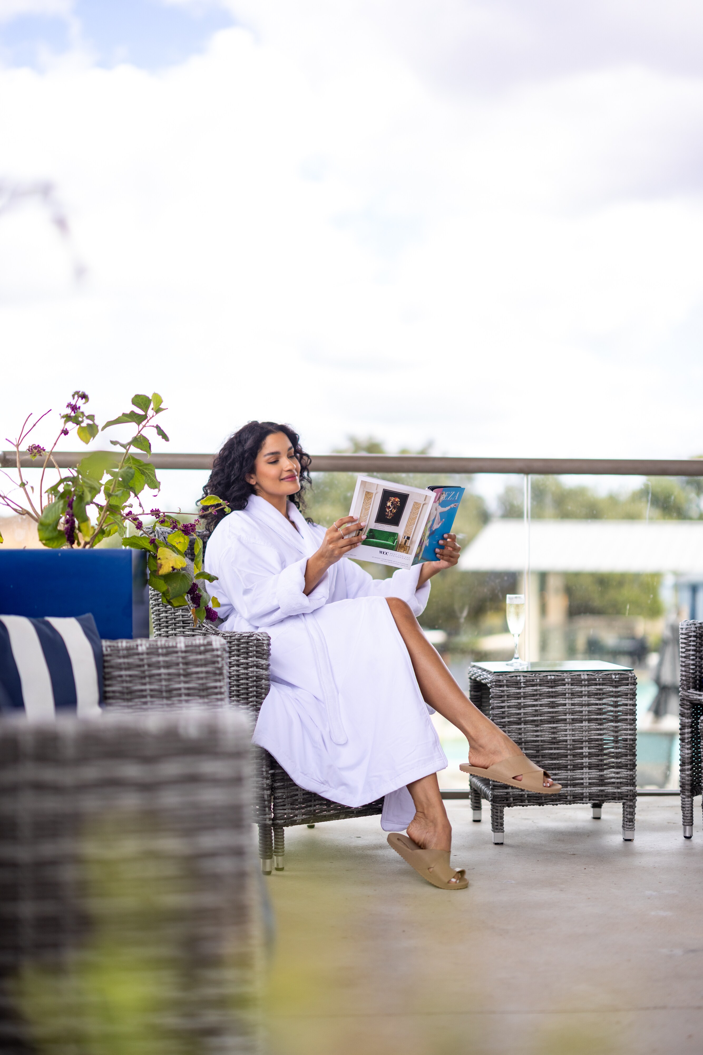 Woman relaxing in robe on balcony, reading a magazine with drink at Lakeway Resort & Spa, Texas