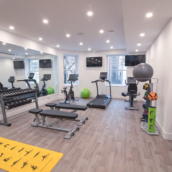 A well-equipped gym with exercise equipment, weights, and TVs.