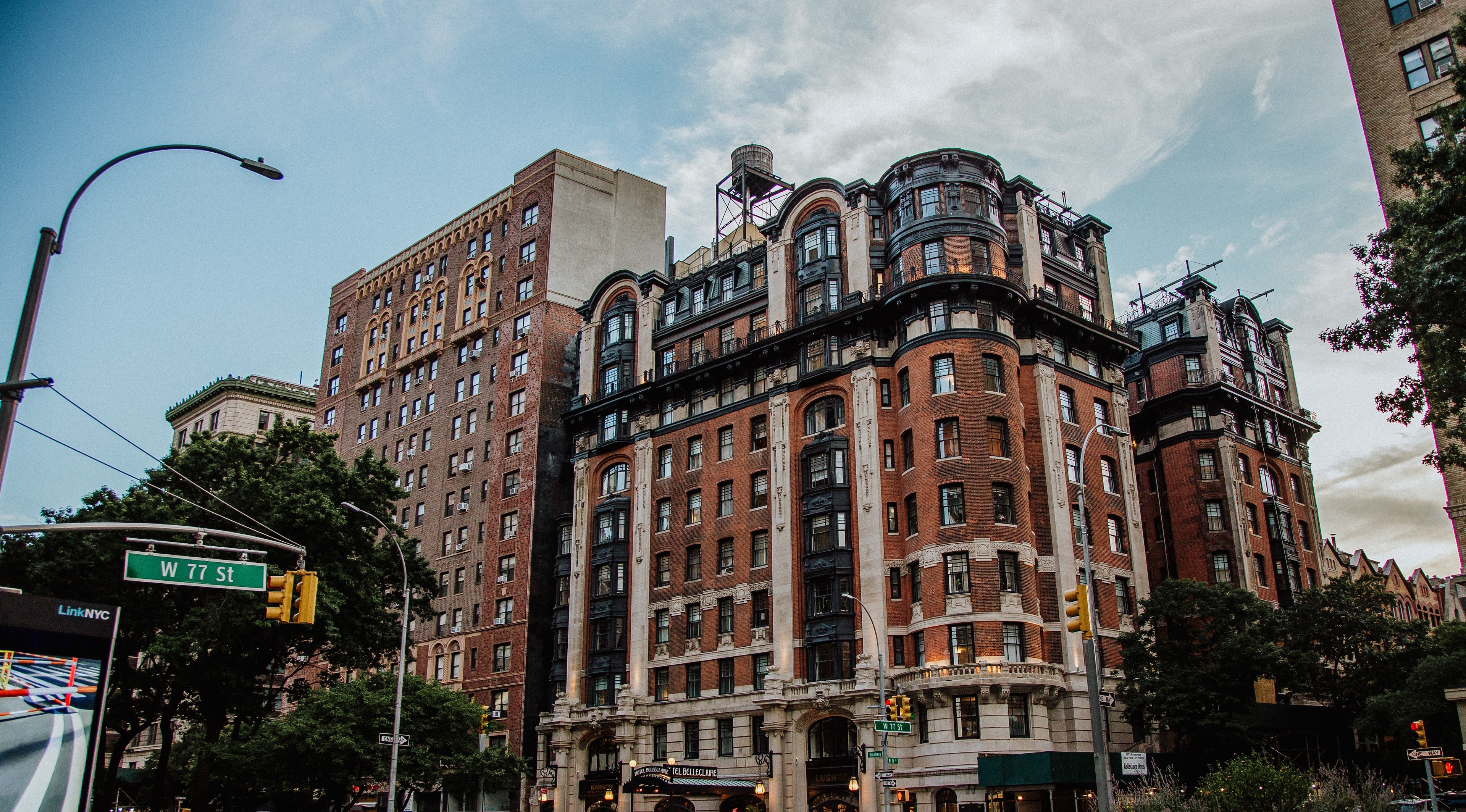 A large, historic hotel building with red brick and ornate details, balconies, and a water tower, set against a blue sky with clouds.
