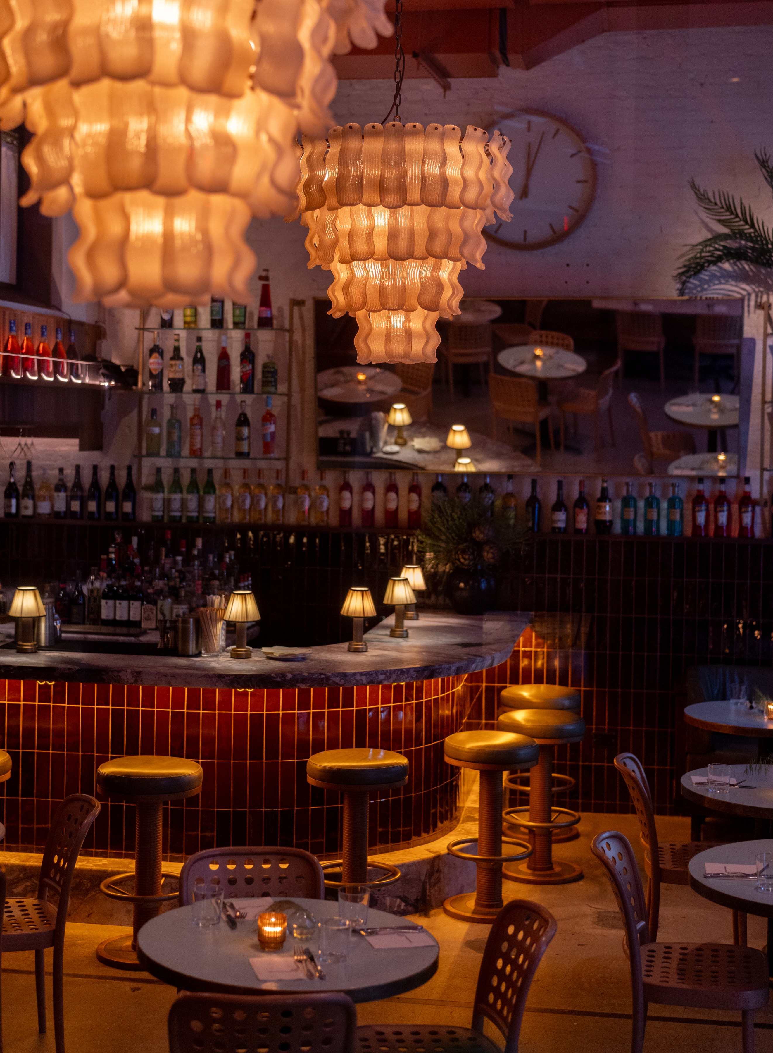 A dimly lit bar with a curved counter, stools, and bottles on shelves.