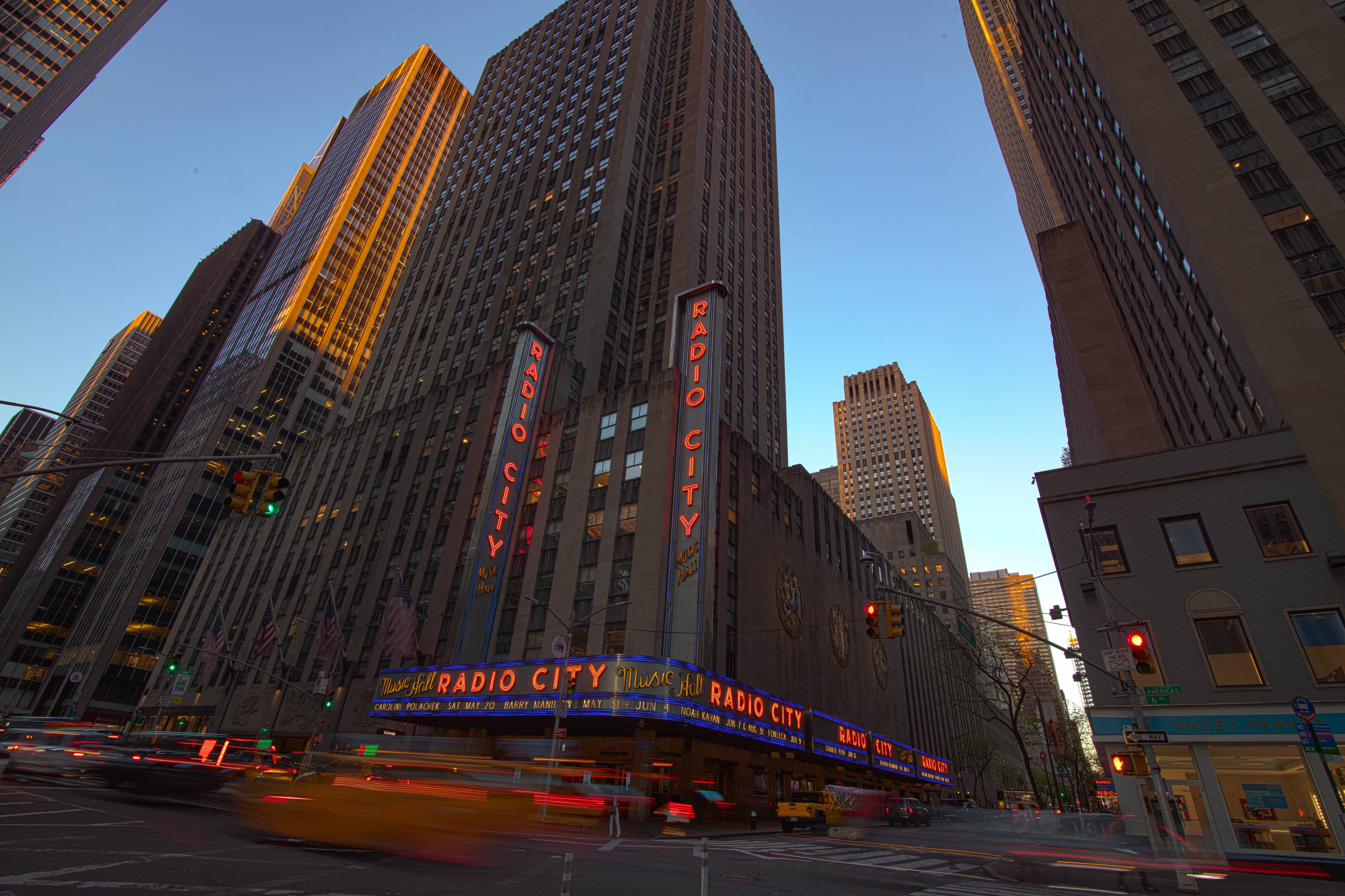 A tall building with a neon sign on a city street