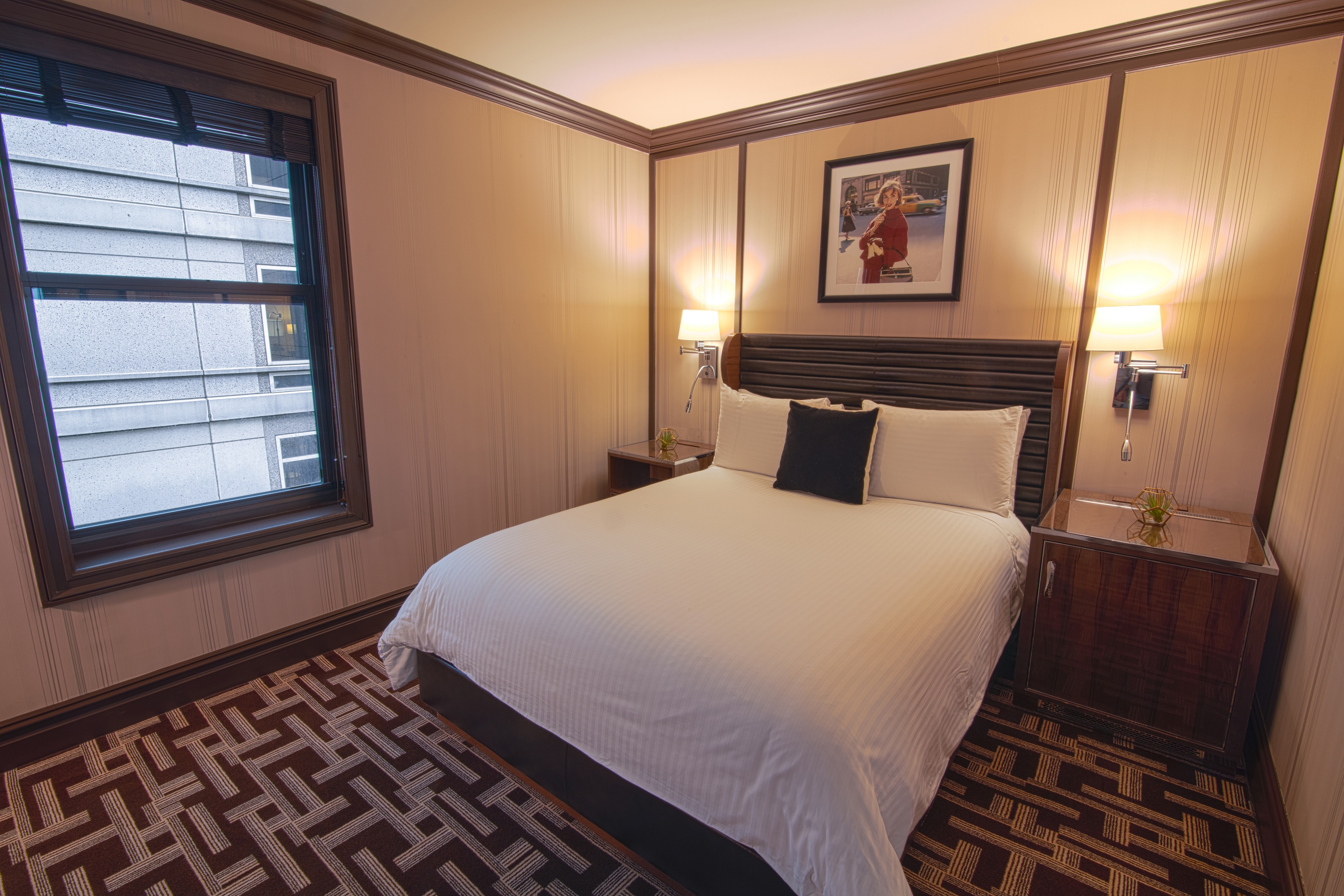 A hotel room with a large bed, two nightstands, and a window.