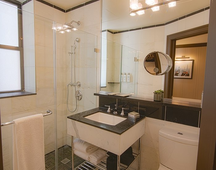 A clean and modern bathroom with a glass-enclosed shower, a double vanity, and a toilet.