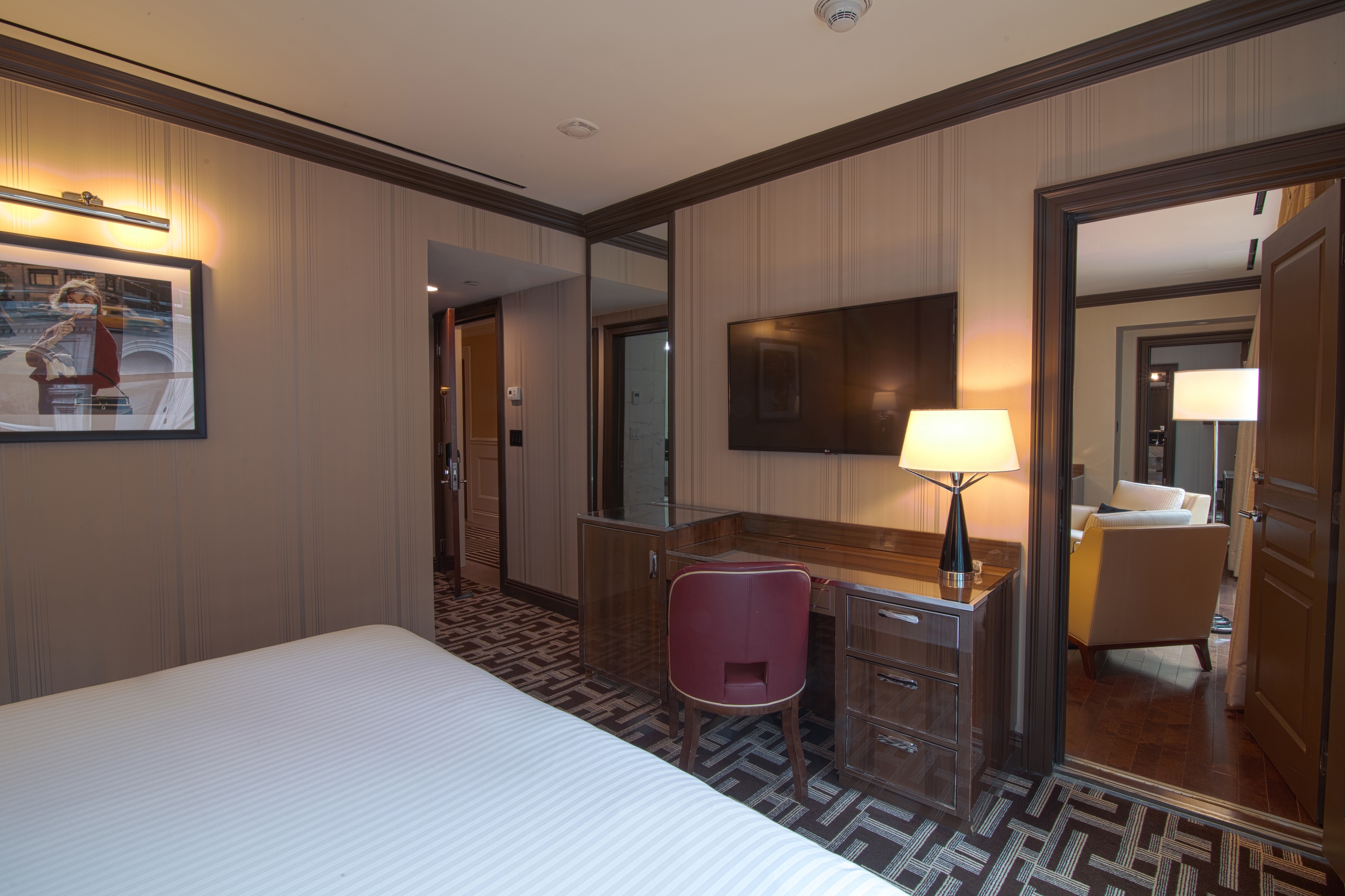 A hotel room with a bed, desk, chair, and TV