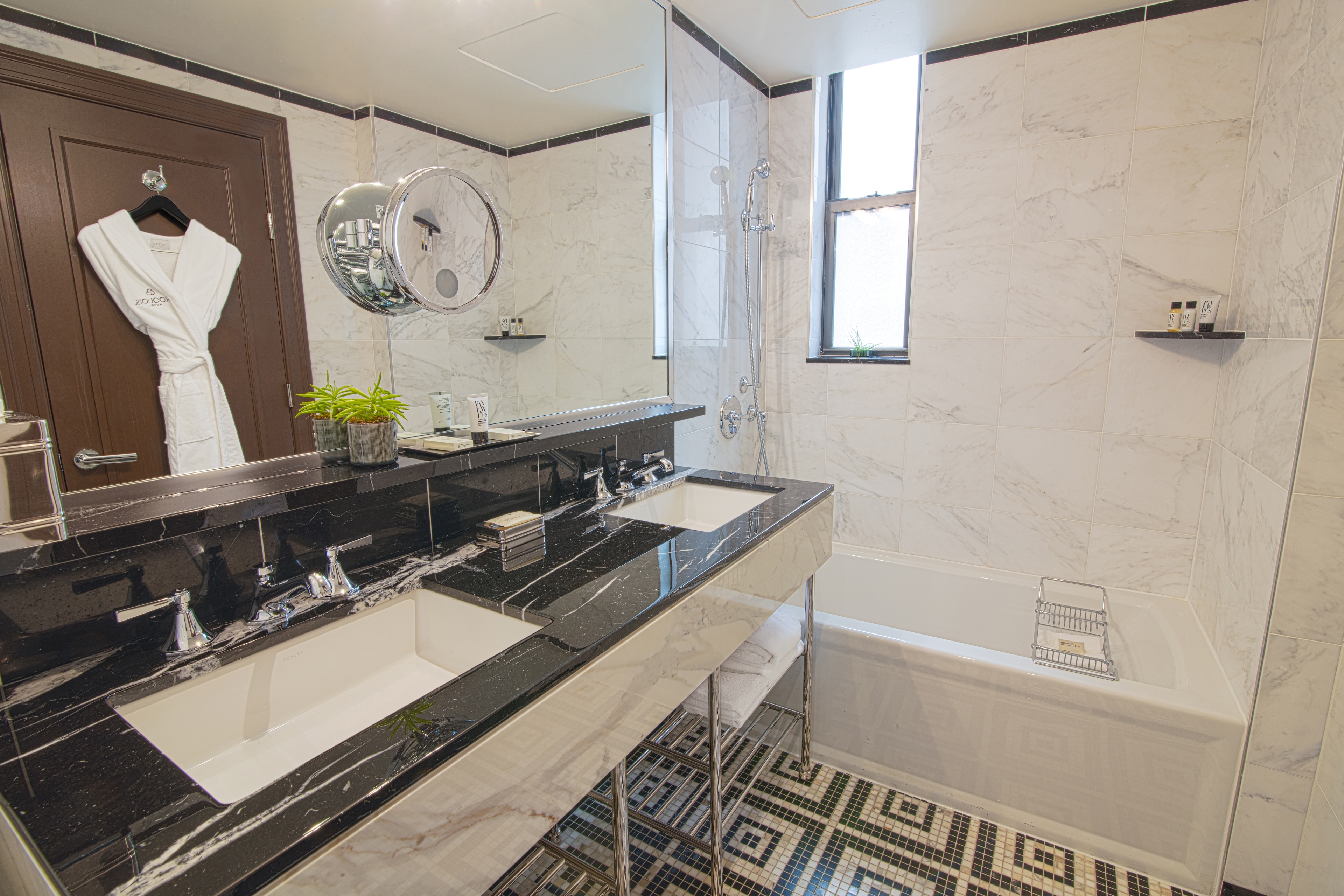 A modern bathroom with a double vanity, bathtub, and shower.