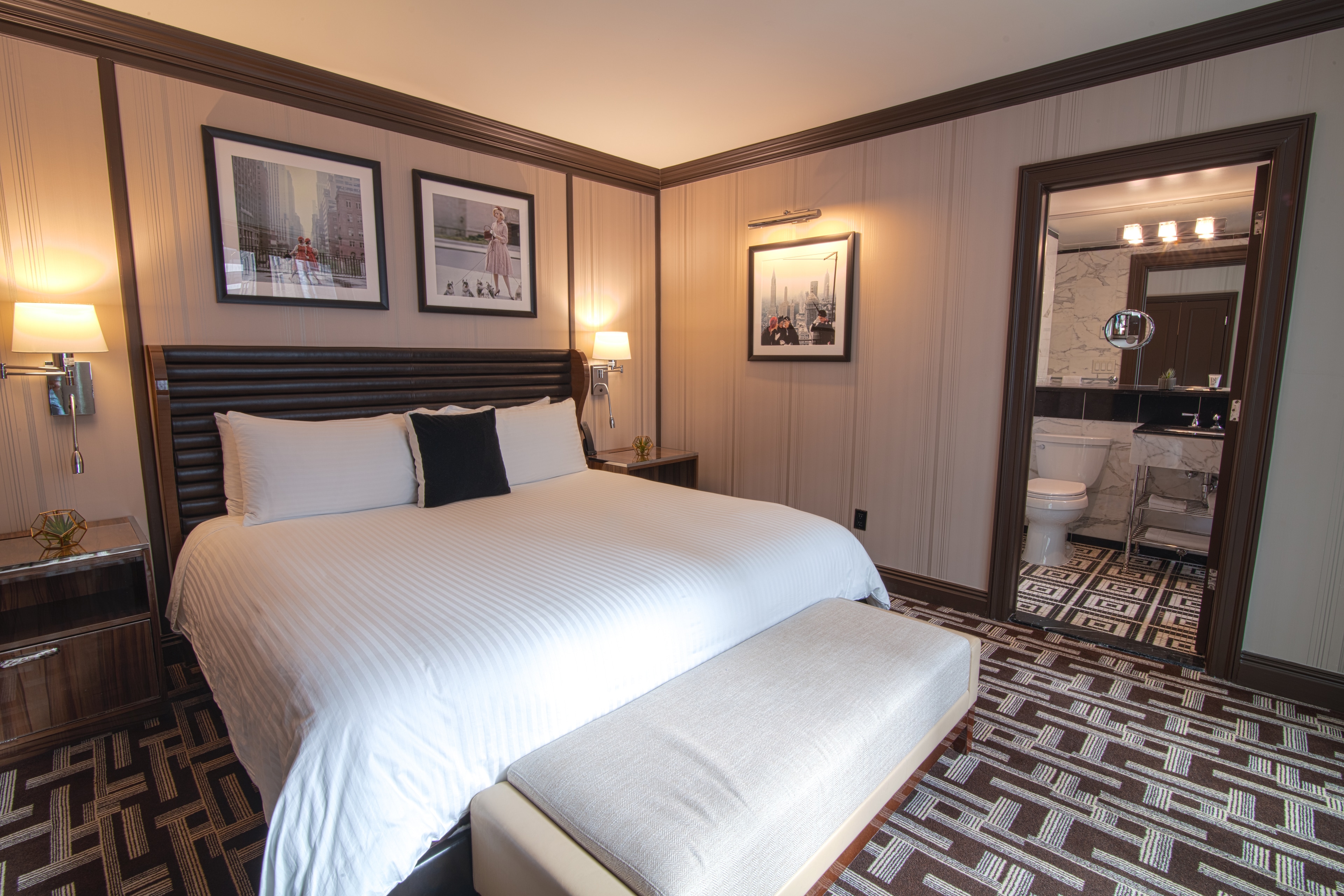 A hotel room with a large bed, two nightstands, and a bathroom in the background.