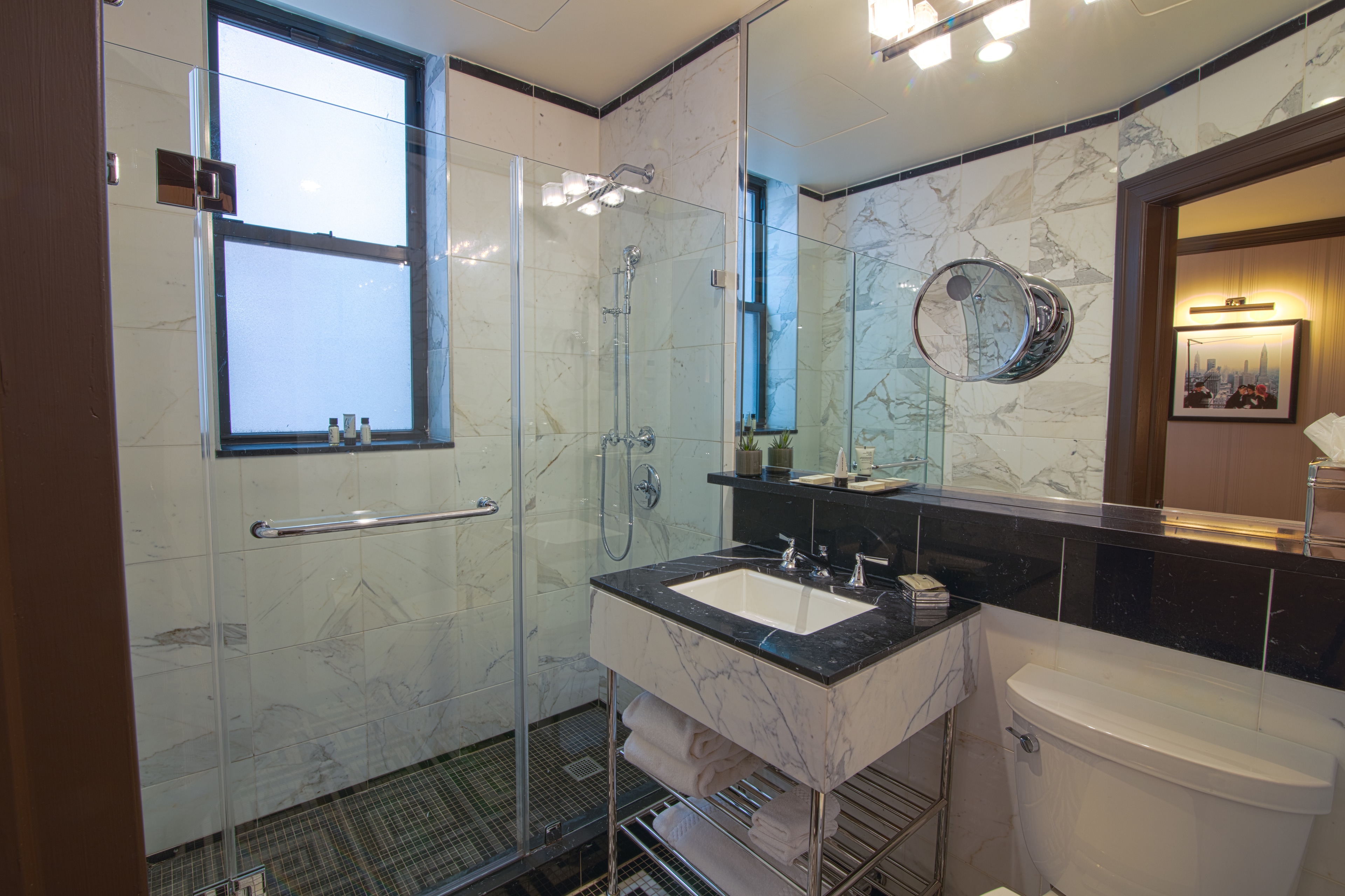 A modern bathroom with marble tiles, a glass-enclosed shower, and a double sink vanity.